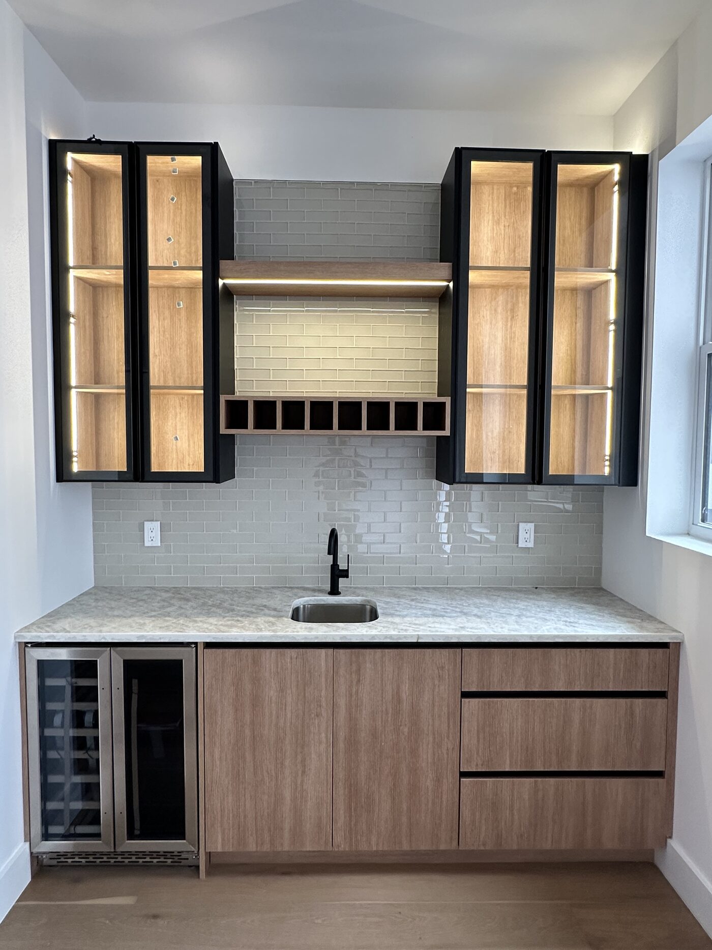 Bar run with black-framed glass display cabinets, LED channels in the shelves, and integrated wine storage.