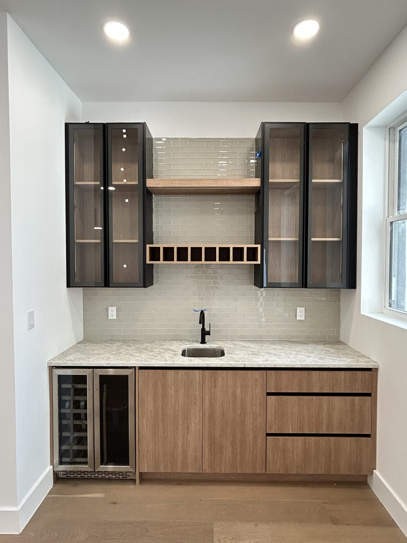 Black-framed display cabinetry with lit shelves, built exactly like the wardrobe runs.