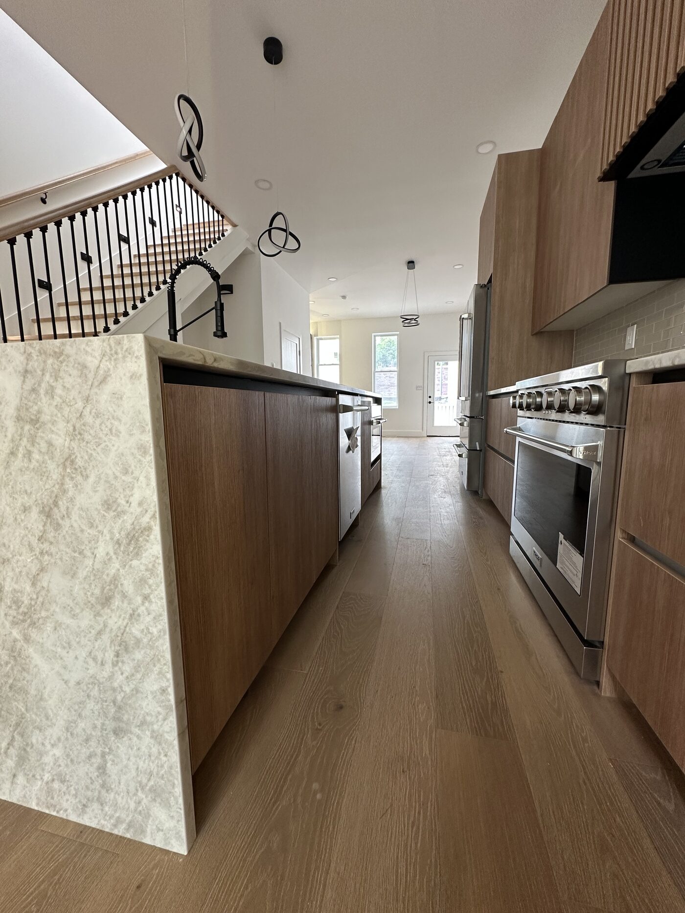 Full-height island in the same veneer, running into an open stair as one continuous run of casework.