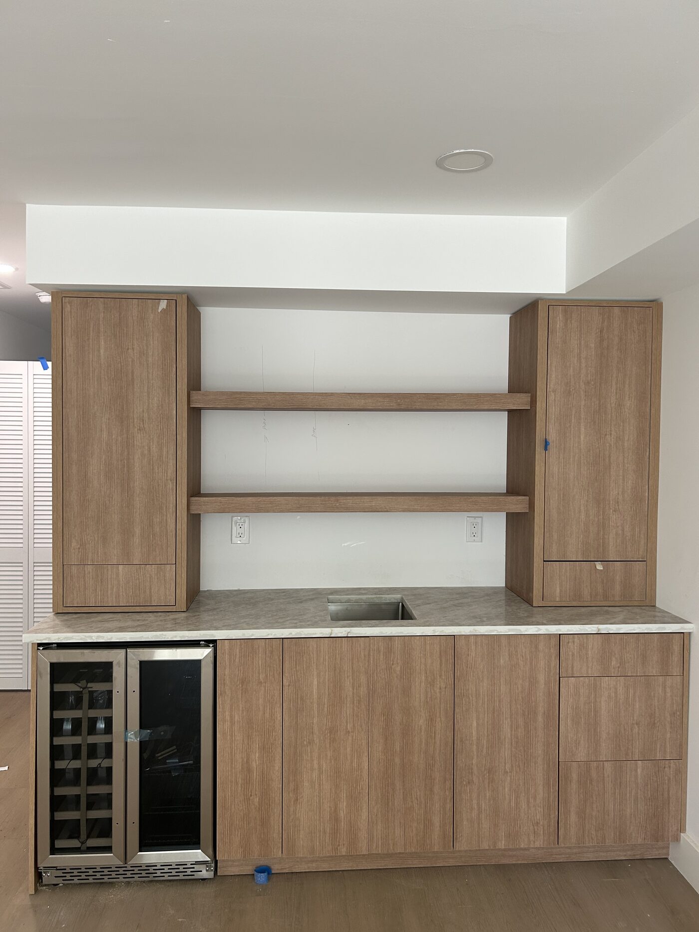 Open shelving over a stone counter, with an undercounter wine column built into the run.