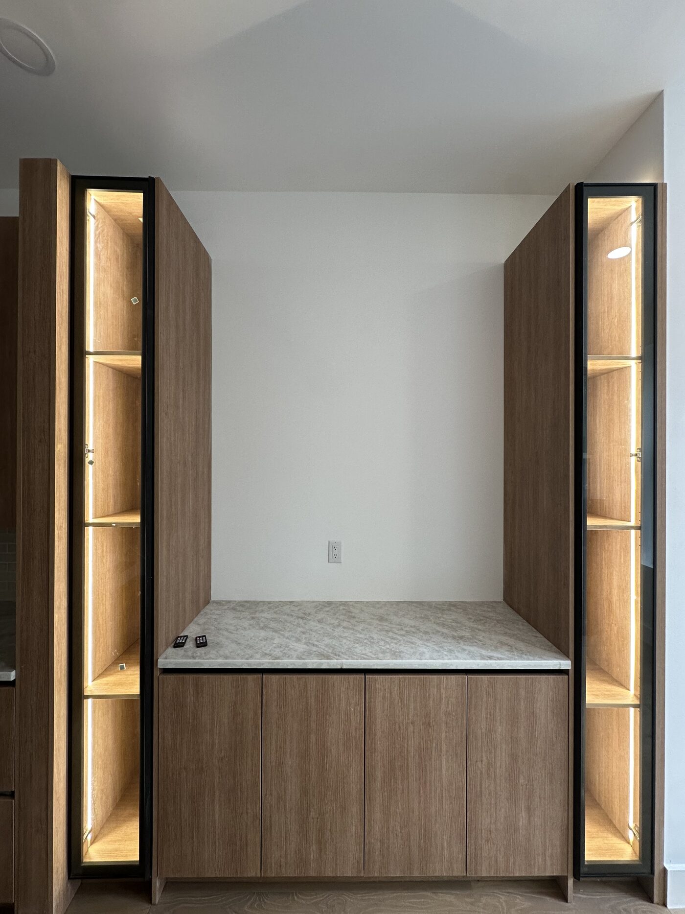 Tall glass-front wardrobe cabinets with LED in the frame, flanking a bench niche.